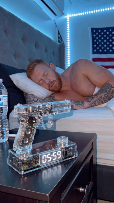 MAGSTAND transparent pistol-shaped alarm clock on a nightstand showing 06:00